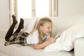 Blond little girl lying on home sofa couch using internet app on digital tablet pad on digital tablet pad Royalty Free Stock Photo