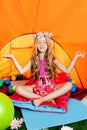 Blond little girl practicing yoga in camping tent