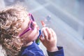 Blond little girl with sunglasses playing with soap bubbles Royalty Free Stock Photo