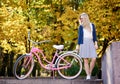 Blond long-haired attractive girl on pink lady bicycle in sunny autumn park on trees background. Royalty Free Stock Photo