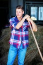 Blond man at a barn holdiing pitchfork with hay Royalty Free Stock Photo