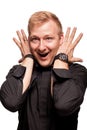 Young blond man in a black shirt, watches and bracelet is making faces, isolated on a white background Royalty Free Stock Photo