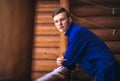 Blond man in a blue sports suit in a wooden house