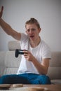 Blond man of European descent throws up his hands and throws down the controller for a lost game. A middle-aged man in a white T- Royalty Free Stock Photo