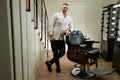 Blond man with mobile phone and laptop stands in barbershop
