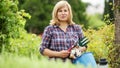 blond mature woman holding horticultural tools