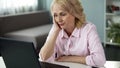 Blond middle-aged woman feeling bored watching online video, falling asleep Royalty Free Stock Photo