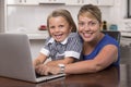 Blond mother woman together with her young beautiful and sweet little girl 6 to 8 years old sitting at home kitchen enjoying with Royalty Free Stock Photo