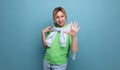 blond positive bright girl in casual outfit shows five fingers on a blue background with copy space