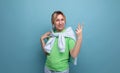 blond positive bright girl in a casual outfit shows two fingers on a blue background with copy space