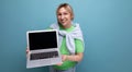 blond positive cute woman consultant in casual outfit showing screen with mockup on laptop on blue background