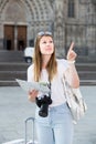 Blond positive young woman holding map in hands