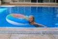 Blond preschool girl playing with float in the swimmimg pool on a beautiful summer day. Royalty Free Stock Photo