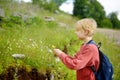 Blond preteen boy picks wild flowers during summer family hiking. Cute kid collects a bouquet for his mom. Inquisitive child Royalty Free Stock Photo