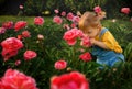 Blond pretty little girl is smelling peonies