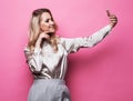 pretty woman taking photo makes self portrait on smartphone over pink background Royalty Free Stock Photo