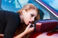 Blond putting lipstick on using the car mirror Royalty Free Stock Photo