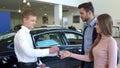 Salesman gives the car key to the couple at the dealership Royalty Free Stock Photo