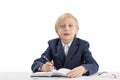 Blond schoolboy sits at a desk with a pen and listens attentively to the teacher. First grader in class. Education concept