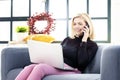 Blond senior woman talking with somebody on her mobile phone and using laptop at home Royalty Free Stock Photo