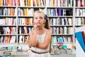 Blond smart girl child bemused a lot of books in a bookstore