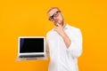 Blond smart smiling man in white shirt with laptop with mockup on yellow background