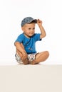 Blond smiling boy sitting on the table wearing baseball cap Royalty Free Stock Photo