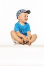 Blond smiling boy sitting on the table wearing baseball cap Royalty Free Stock Photo