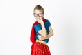Happy and cool blond supergirl with glasses and red robe und blue shirt is posing in the studio Royalty Free Stock Photo