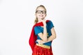 Happy and cool blond supergirl with glasses and red robe und blue shirt is posing in the studio Royalty Free Stock Photo