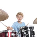 Blond teen boy plays drums at drumkit in studio against white ba Royalty Free Stock Photo