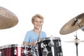 Blond teen boy plays drums at drumkit in studio against white ba Royalty Free Stock Photo