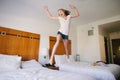 A blond teen girl jumping on beds in a hotel.