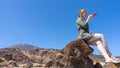 Blond teen giving instruction to intelligence assistance by the microphone of the smart phone. Caucasian woman sitting in volcano