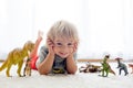 Blond toddler child, playing with dinosaurs at home