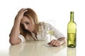 Blond wasted and depressed alcoholic drunk woman drinking white wine glass desperate sad