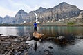 Blond woman by alpine lake enjoying the mountain view on a rainy day. Royalty Free Stock Photo