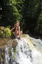 Blond woman in bikini by waterfall