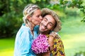 Blond woman in blue dress kissing handsome man outdoors in nature