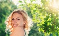 Blond woman, curly hair in green nature. Sunny summer