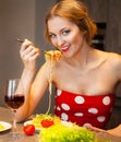 Blond woman eating spaghetti in the kitchen at home Royalty Free Stock Photo