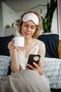Blond Woman Have Cup Of Tea Coffee And Looking At Phone Early Morning In Her Bed Royalty Free Stock Photo