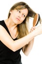 Blond woman having problem with brushing long straight tangled hair with hairbrush Royalty Free Stock Photo