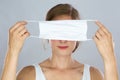 Blond woman holding face mask covering her eyes in front of her head Royalty Free Stock Photo