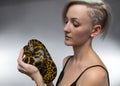 Blond woman holding yellow anaconda