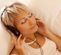 Woman in living room listening to MP3 player smiling Royalty Free Stock Photo