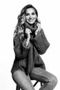 Blond woman with long curly hair sitting on chair dressed in comfy oversize knitted sweater bw photo