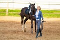 Blond woman with long hair jockey rider on a bay horse, in a paddock on a ranch Royalty Free Stock Photo