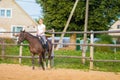 Blond woman with long hair jockey rider on a bay horse, in a paddock on a ranch Royalty Free Stock Photo