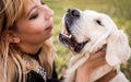 A blond woman patting her retriever dog in the park Royalty Free Stock Photo